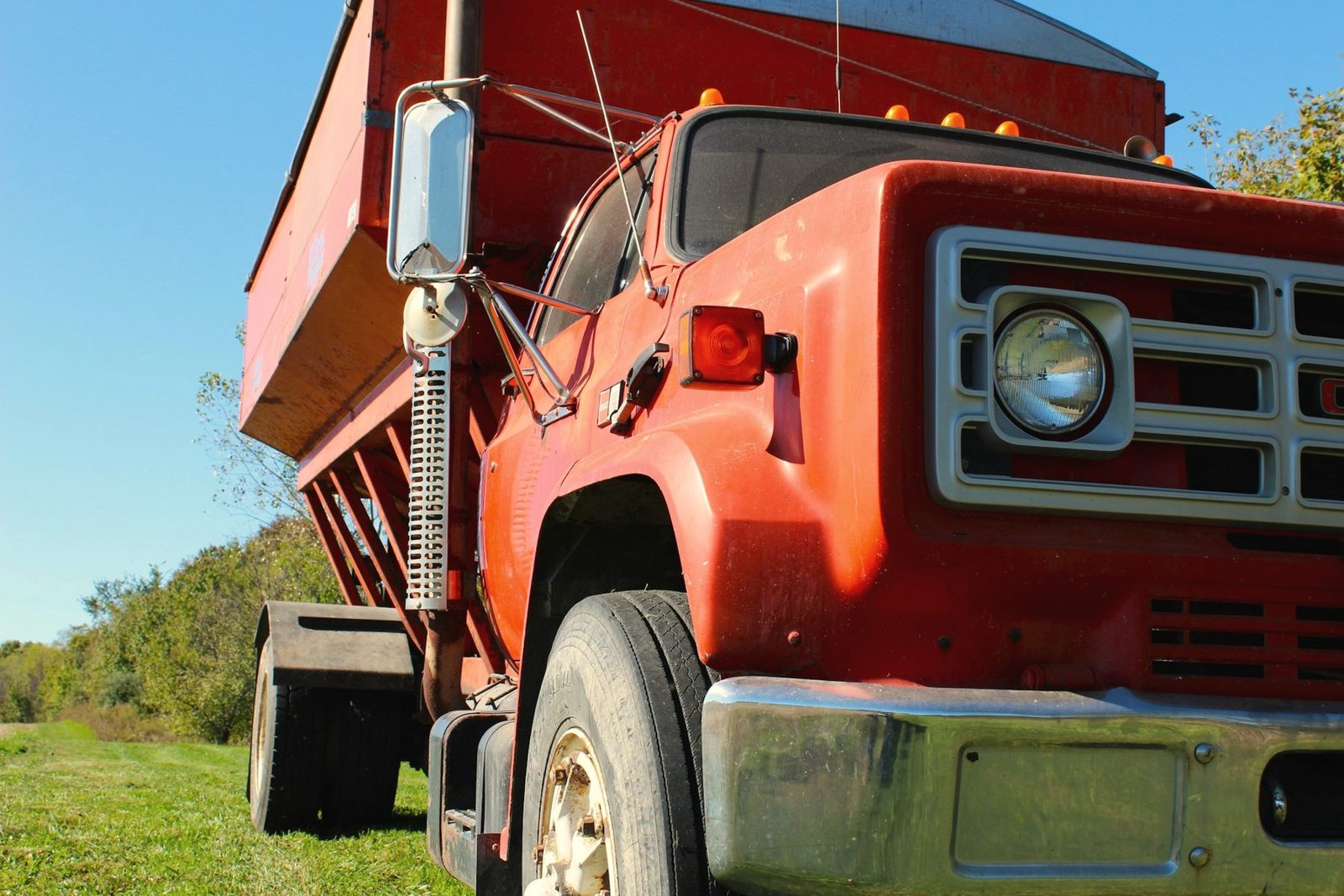 Front of an older red grain truck parked on grass