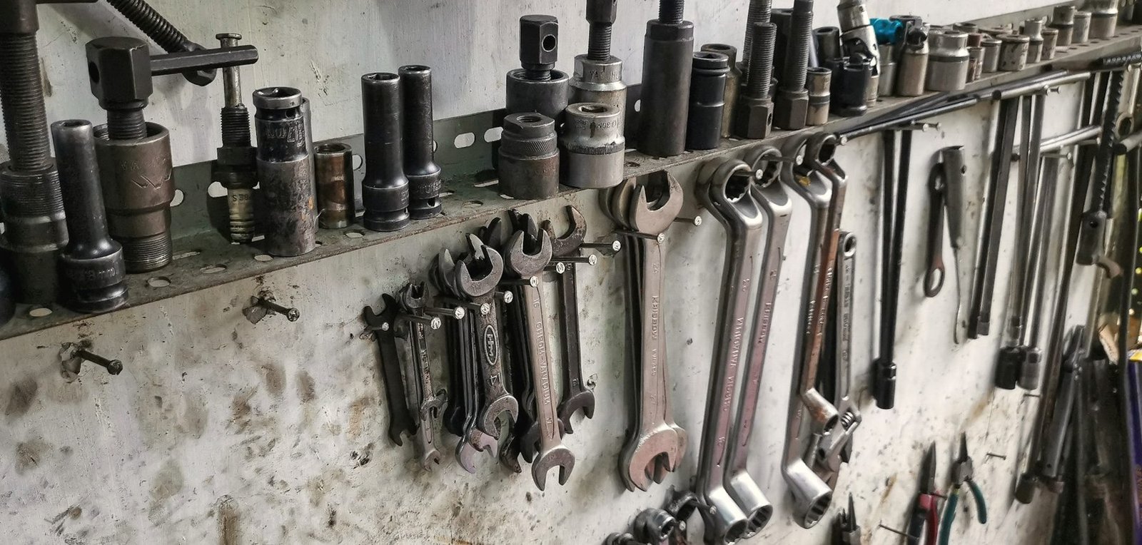 Sockets and wrenches hanging on a workshop wall rail