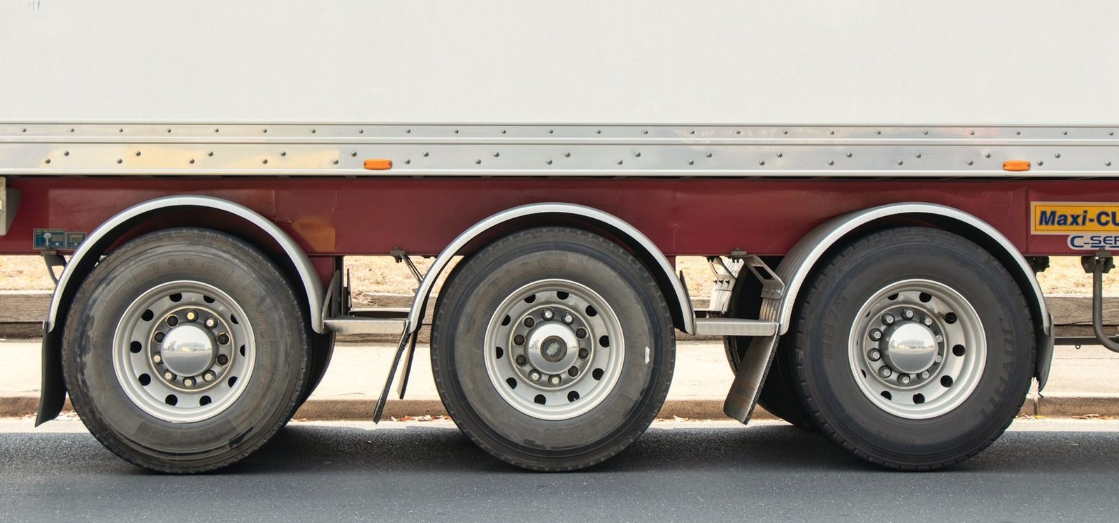 Three axles and wheels of a semi trailer seen from the side
